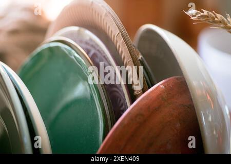 Une image en gros plan de plusieurs assiettes en céramique empilées dans un cadre de cuisine. Les plaques sont de différentes couleurs et tailles, avec une plaque verte au premier plan. Banque D'Images