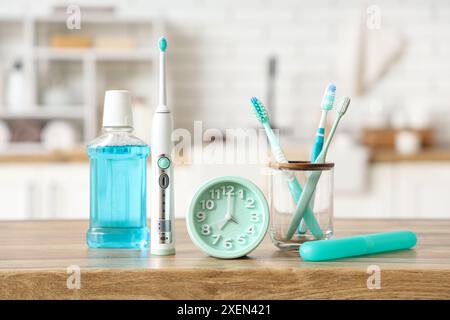 Support avec brosses à dents, rince-bouche, étui et horloge sur table dans la salle de bain Banque D'Images
