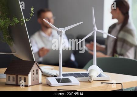 Modèles d'éoliennes avec panneau solaire portable et ampoule sur la table de l'ingénieur dans le bureau, gros plan Banque D'Images