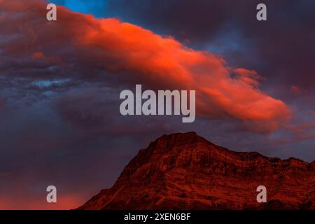 Nuage rouge éclatant spectaculaire au coucher du soleil au-dessus d'un sommet de montagne éclatant dans le parc national des Lacs-Waterton ; Waterton, Alberta, Canada Banque D'Images