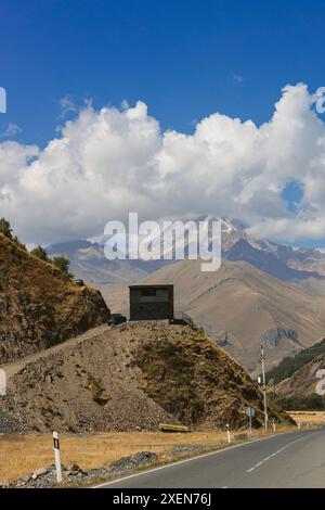 Itinéraire routier pittoresque avec vue sur les montagnes du Caucase sous des nuages cumulus bouillonnants et un ciel bleu avec côté, chemin de terre pour belvédère à Tru... Banque D'Images