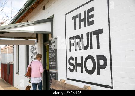 Une femme d'âge moyen commande du café à emporter au café de la boutique de fruits dans le centre-ville de Walcha, NSW régional, Australie, 2024 Banque D'Images