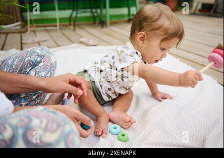 Adorable bébé garçon jouant avec une pyramide en bois coloré de bois écologique, jouant à des jeux éducatifs et de développement, développant la motricité et la pensée Banque D'Images