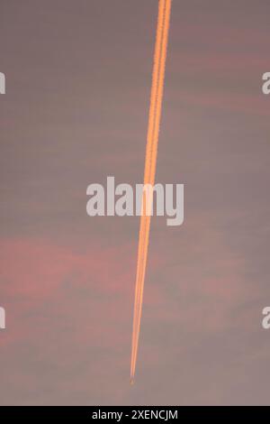 L'avion traîne dans le ciel rétroéclairé par la lumière du coucher du soleil ; Makassar, Sulawesi du Sud, Indonésie Banque D'Images