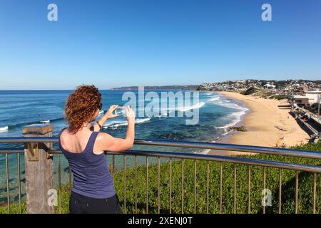 Une femme prend une photo avec son téléphone intelligent de Bar Beach et Merewether - Newcastle Australie. La région de Newcastle abrite un littoral étonnant. Banque D'Images