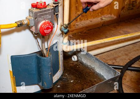 Tournevis fermant le robinet de vidange sur le chauffe-eau Banque D'Images