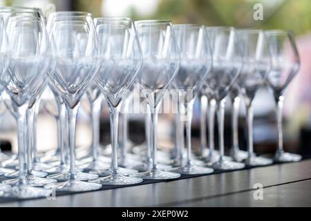 Une vue rapprochée de plusieurs verres à vin vides disposés en rangées sur une table, prêts pour un événement ou une célébration. Banque D'Images