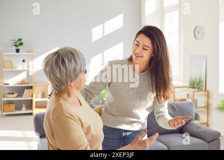 Heureuse fille adulte visitant sa mère âgée aînée dans le salon à la maison Banque D'Images