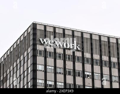 Brooklyn, NY - 15 janvier 2023 : WeWork coworking space Company signe sur un grand immeuble de bureaux avec fond de ciel gris à Brooklyn, New York City. Banque D'Images