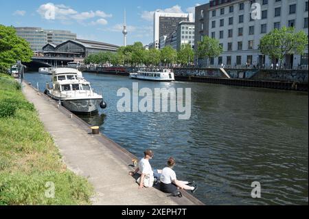 17.05.2024, Berlin, Allemagne, Europe - les gens sont assis sous le soleil chaud du printemps sur la rive de la rivière Spree dans le district de Mitte. Banque D'Images