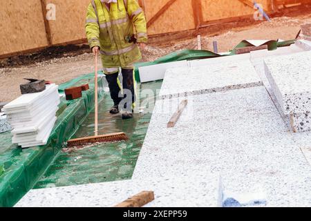 Constructeur plaçant des panneaux isolants de polystyrène sur la membrane d'étanchéité pendant la construction de plancher. Concept d'économie d'énergie Banque D'Images