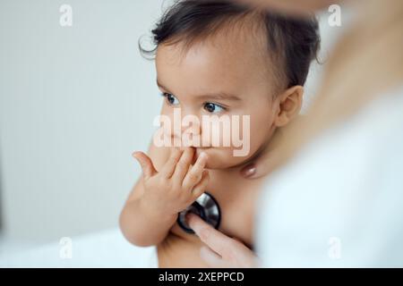 Bébé, stéthoscope et mains du médecin en clinique pour le check up, le rythme cardiaque et le progrès pour la croissance. Enfant, pédiatre et soins de santé avec équipement pour Banque D'Images