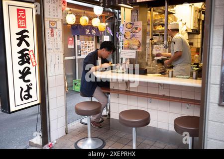 Tokyo, Japon - 15 juin 2024 : les clients se régalent de la cuisine japonaise à Omoide Yokocho, une ruelle populaire avec des stands de nourriture situés dans la ville de Shinjuku Banque D'Images