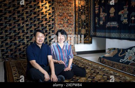 (240629) -- PÉKIN, 29 juin 2024 (Xinhua) -- Ji Yu pose pour une photo avec son mari Li Dongyang dans son studio à Pékin, capitale de la Chine, le 27 juin 2024. Le tapis du palais de Pékin est un magnifique exemple des techniques traditionnelles de tissage de tapis de Chine. Connu pour ses processus de production complexes et ses beaux motifs, le tapis du palais représente le summum de l'art du tissage chinois. La production comprend quatre étapes principales : teinture avec des herbes traditionnelles chinoises, création de patrons, tissage et façonnage, et enfin, finitions. En tant que l'un des huit artisanats impériaux de Pékin, l'Ar Banque D'Images