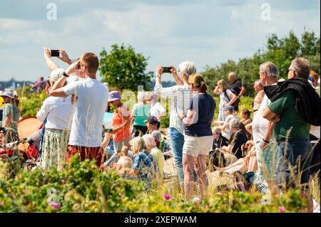 Kiel, Allemagne. 29 juin 2024. Les spectateurs regardent les voiliers depuis la plage pendant la parade windjammer sur le fjord de Kiel. Crédit : Jonas Walzberg/dpa/Alamy Live News Banque D'Images