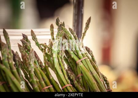 Cette image vibrante présente des lances d'asperges fraîches soigneusement emballées et exposées à la vente sur un marché animé de Belgrade. Les légumes verts croustillants Banque D'Images