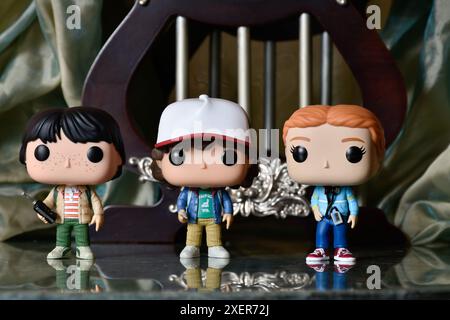 Funko Pop figurines de Dustin, Max et Mike de la série télévisée d'horreur populaire Stranger Things. Plancher de réflexion, rideau vert, palais vintage. Banque D'Images