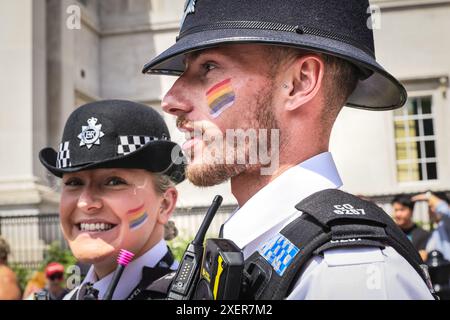 Londres, Royaume-Uni. 29 juin 2024. Met les officiers de police se joignent à l'esprit de fierté avec la peinture arc-en-ciel pour le visage tout en gardant le public en sécurité. Les participants et les spectateurs s’amusent tout au long du parcours de la Pride in London 2024 Parade. Le défilé progresse de Hype Park le long de Piccadilly jusqu'à Whitehall, et une fête à Trafalgar Square. Il célèbre la diversité et la communauté LGBT. Crédit : Imageplotter/Alamy Live News Banque D'Images