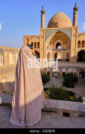 Femme en Iran en prenant une photo de la mosquée Agha Bozorg, cour intérieure de Kashan, Iran, moyen-Orient. Banque D'Images