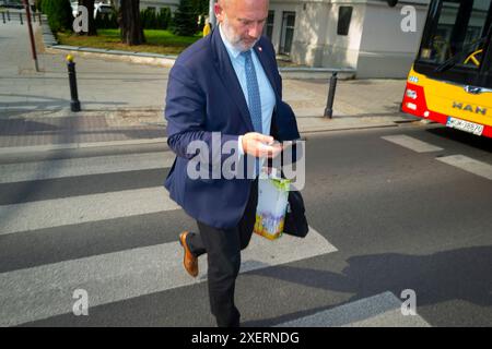 Varsovie, Pologne. 28 juin 2024. Un homme d'affaires en costume et cravate est vu regarder son téléphone portable alors qu'il traversait une rue à Varsovie, en Pologne, le 28 juin 2024. (Photo de Jaap Arriens/Sipa USA) crédit : Sipa USA/Alamy Live News Banque D'Images