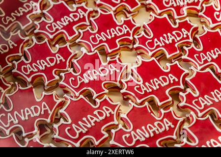 Étalage au détail de biscuits rouge vif en forme de feuille d'érable portant le mot Canada dans une vitrine de boulangerie. Banque D'Images