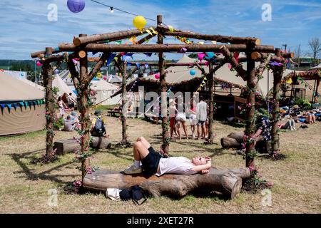 Glastonbury, Royaume-Uni. Jour 4, 29 juin 2024. Un festivalier se détend sur un banc dans l'arène du parc au Glastonbury Festival, Worthy Farm dans le Somerset. Date de la photo : samedi 29 juin 2024. Le crédit photo devrait se lire : David Jensen / Alamy Live News Banque D'Images