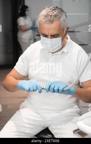 Le professionnel dentaire organise méticuleusement les outils dans une clinique désinfectée pour l'examen du patient, en respectant les normes de sécurité et d'hygiène Banque D'Images