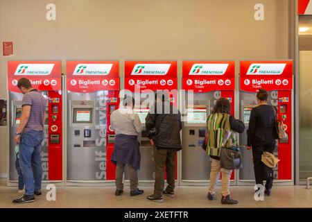 Les passagers utilisant les distributeurs automatiques de billets de train intérieurs en libre-service italien Trenitalia pour acheter leurs billets de train Banque D'Images