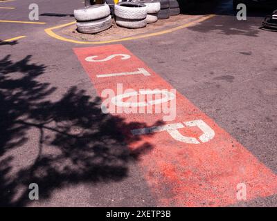 Panneau stop peint sur l'asphalte d'une piste de karting. Le panneau est blanc avec de la peinture rouge autour. Banque D'Images