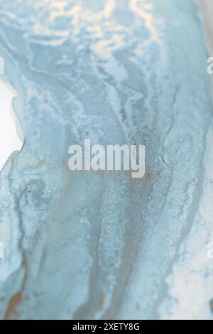 Une image abstraite en gros plan présentant des motifs tourbillonnants dans des tons de bleu et de blanc. Les textures ressemblent à de l'eau ou de l'encre, créant un rêve, éthéré Banque D'Images