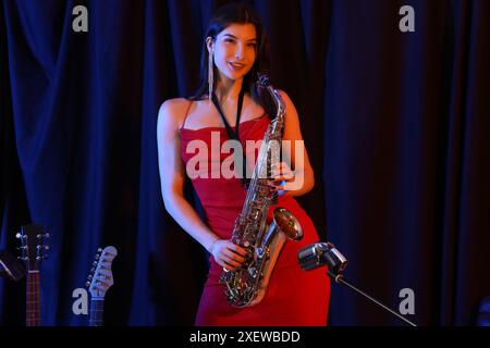 Belle femme avec saxophone se produisant sur scène Banque D'Images