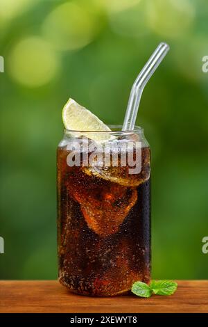 verre de cola froid avec des glaçons ou cocktail cuba libre sur une table en bois à l'extérieur Banque D'Images