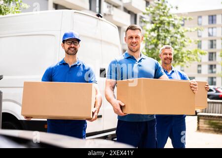 Camions déménageurs efficaces transportant des boîtes pour la relocalisation de la maison avec un chauffeur professionnel et installateur de matériel certifié en bleu. Banque D'Images