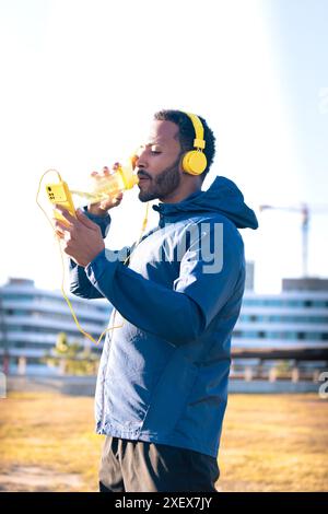 Homme coureur buvant de l'eau d'une bouteille de sport à l'extérieur. Banque D'Images