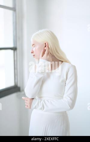 Modèle de fille albinos debout dans le fond blanc de studio. Femme inclusive. Banque D'Images