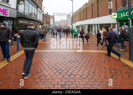 Scène de rue animée à Derby, en Angleterre, avec des gens marchant et faisant du shopping par une journée humide et couverte, mettant en valeur le mode de vie urbain dynamique au Royaume-Uni Banque D'Images