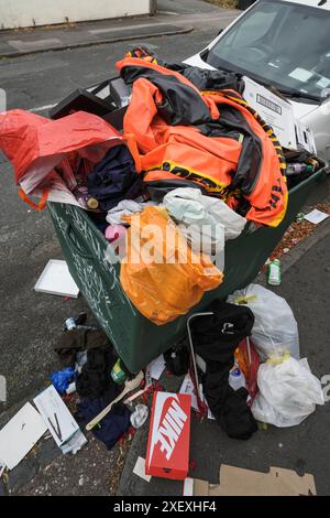 Selly Oak, Birmingham, le 30 juin 2024 - Un canot orange dégonflé est jeté dans un bac de conseil débordant. - Les rues résidentielles de Birmingham ont été transformées en décharges car les étudiants déménagent à la fin de leurs contrats. La plupart des étudiants fréquentent l'Université de Birmingham qui est à environ 800 mètres des rues résidentielles en terrasses Selly Oak. Les routes ont principalement été achetées par les propriétaires qui les louent aux étudiants de premier cycle avec rangée sur rangée de panneaux «pour louer». Crédit : arrêtez Press Media/Alamy Live News Banque D'Images