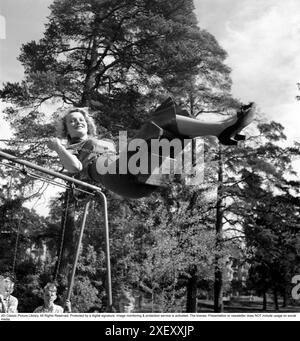 femme des années 1950. Une jeune femme blonde est vue sur une balançoire, allant d'avant en arrière dans les airs. Elle a l'air heureuse et souriante. Suède 1953. Photo Kristoffersson Réf BL95-3 Banque D'Images