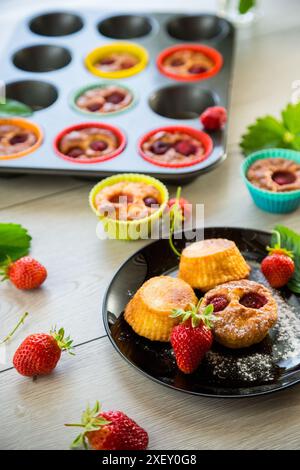 Muffins au lait caillé sucré garnis de fraises, dans une assiette sur une table en bois. Banque D'Images