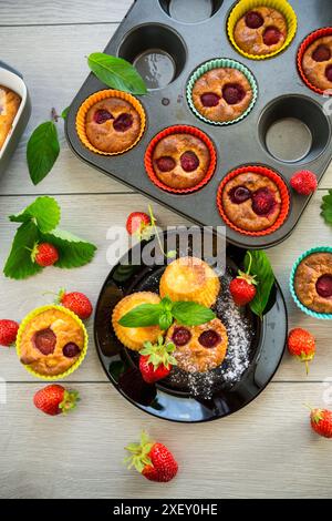Muffins au lait caillé sucré garnis de fraises, dans une assiette sur une table en bois. Banque D'Images