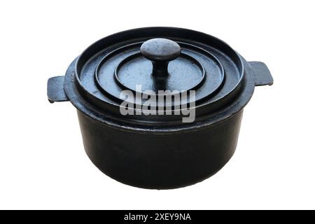 Casserole utilisée en fonte avec couvercle fermé isolé sur fond blanc. Pot noir. Équipement de cuisine usagé. Banque D'Images