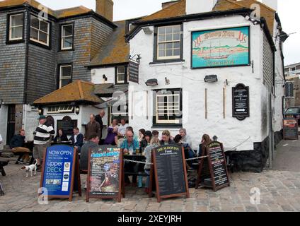 Sloop Inn, St Ives Cornwall, Royaume-Uni - les gens assis à des tables à l'extérieur du pub, manger, boire et bavarder Banque D'Images