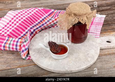 Confiture de pommes de pin. Pot de délicieuse confiture de pommes de pin sur fond clair. Confiture de cônes dans un beau bocal en verre. Une délicatesse hivernale parfumée. Banque D'Images