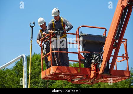 Ouvriers en nacelle élévatrice. Mise en service sur site, diagnostics et tests de maintenance sur les câbles haute tension souterrains et les systèmes SIG basés sur variable Banque D'Images