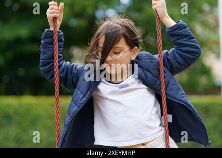 Petite adolescente joyeuse dans des verres sur le terrain de jeu. Concept d'enfance heureuse Banque D'Images