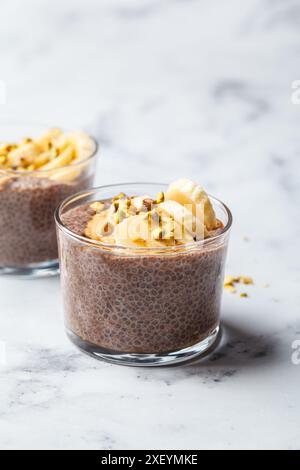 Pudding au chia au chocolat avec banane, pistache et sirop d'érable dans un verre. Banque D'Images