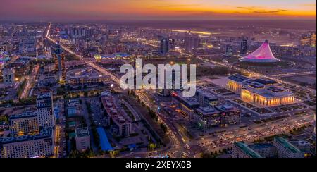 La vue aérienne nocturne du centre-ville d'Astana (Kazakhstan), avec le centre commercial Khan Shatyr, l'opéra d'Astana, l'avenue Kabanbay Batyr et le panorama de la ville Banque D'Images