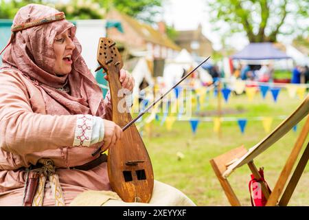 Gros plan d'une femme vêtue d'un costume médiéval chantant et jouant une lyre byzantine également connue sous le nom de lira, avec un stand de musique devant elle. Banque D'Images