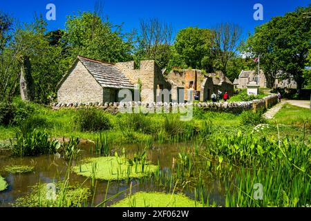 L'étang du village dans Tyneham Village avec les vieilles cottages abandonnés derrière, Tyneham Village, Dorset, Angleterre. Banque D'Images