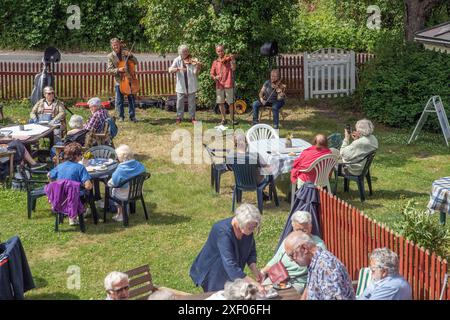 Garden party dans le village avec des musiciens folkloriques jouant en arrière-plan. Mellosa, Flen, Suède Banque D'Images